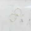 Two 30mm hoop earrings with gold plating and a single pearl on each earring placed side by side on a marble surface